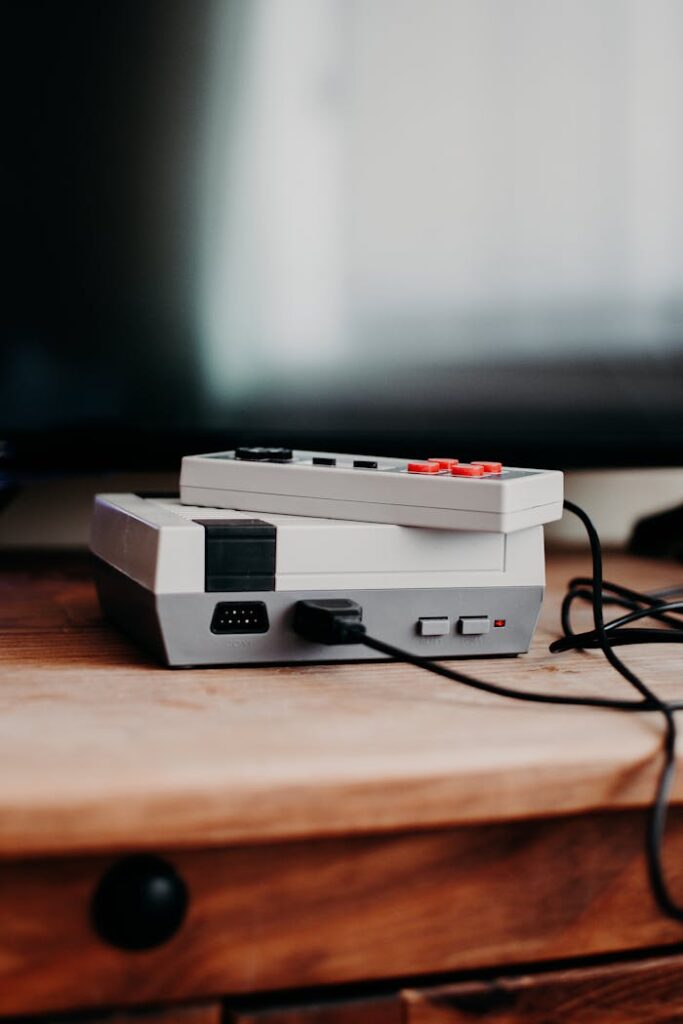 Vintage gaming console and controller on wooden desk, capturing nostalgic essence.